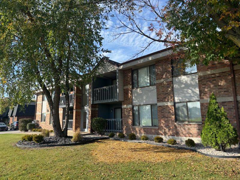 Brick building framed by mature trees and landscaped beds